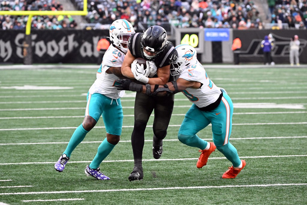 Dolphins cornerback Rasul Douglas (26) and linebacker Jordyn Brooks (20) attempt to tackle Jets tight end Mason Taylor (85) during the fourth quarter of the Jets and Miami Dolphins game in East Rutherford, NJ.