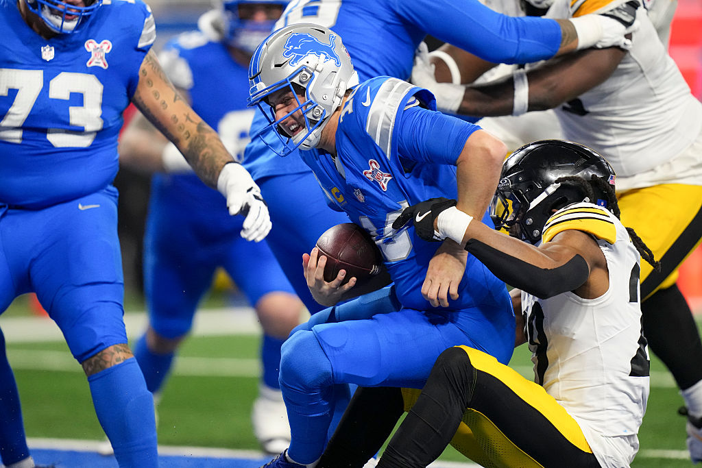 Jared Goff #16 of the Detroit Lions speaks with line judge Daniel Gallagher #85 during the second half of an NFL football game against the Pittsburgh Steelers at Ford Field on December 21, 2025 in Detroit, Michigan. 