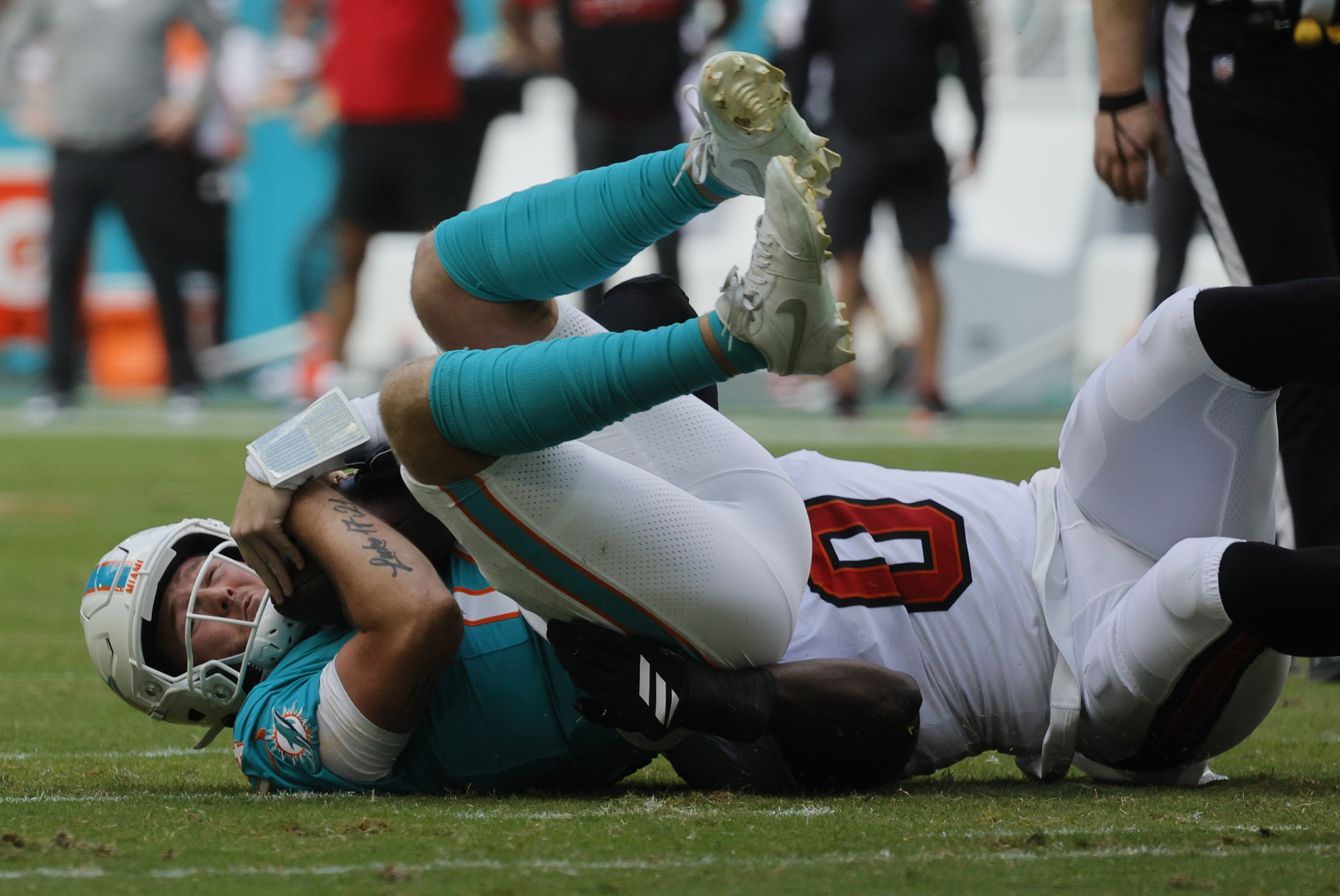 Miami Dolphins quarterback Quinn Ewers (14) is brought down by...