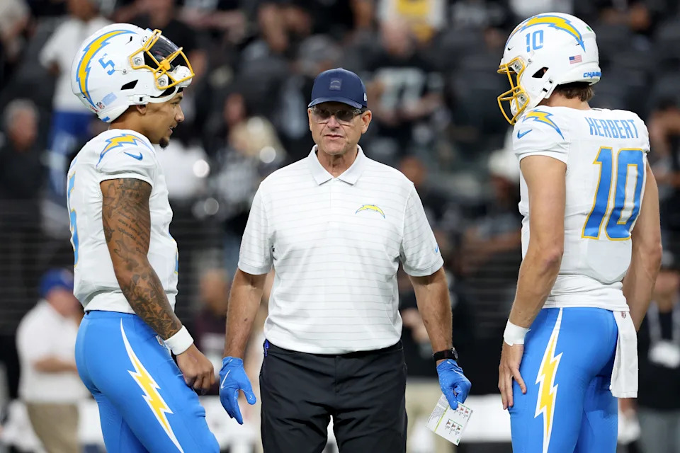Head coach Jim Harbaugh of the Los Angeles Chargers speaks with Justin Herbert #10 and Trey Lance #5.