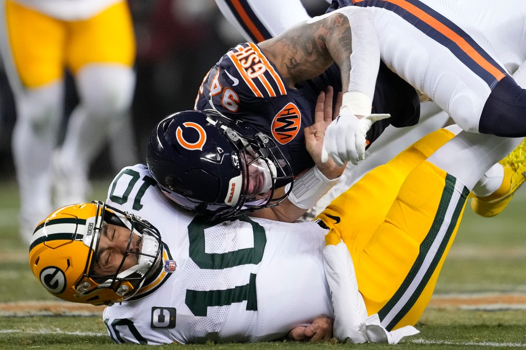 Jordan Love #10 of the Green Bay Packers is hit after his pass by Austin Booker #94 of the Chicago Bears during the first quarter at Soldier Field on December 20, 2025 in Chicago, Illinois.
