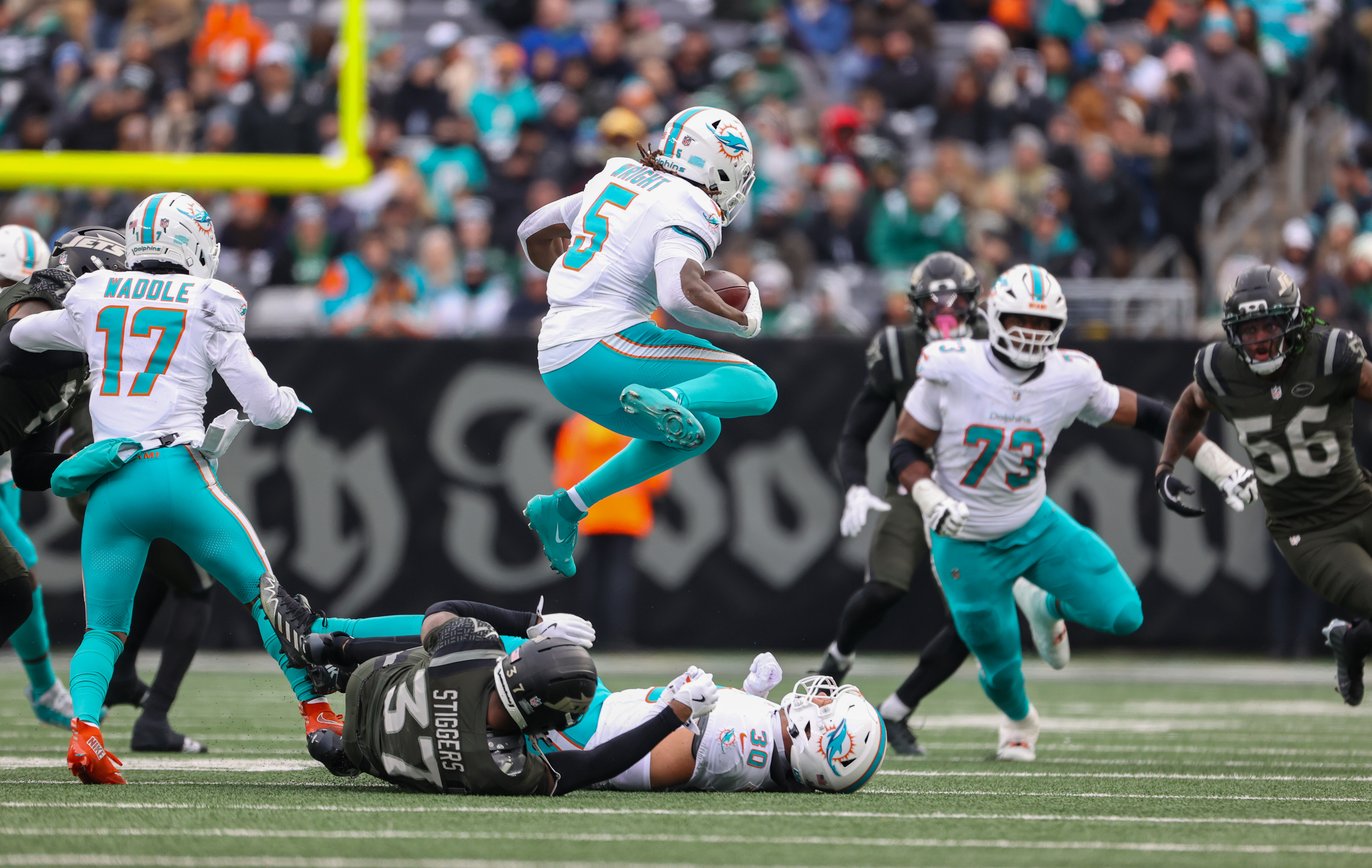 Miami Dolphins running back Jaylen Wright (5) leaps over New York Jets cornerback Qwan'Tez Stiggers (37) who was penalized for a chop block on Dolphins fullback Alec Ingold (30) during the second quarter, Sunday, Dec. 7, 2025 at MetLife Stadium in East Rutherford, N.J.