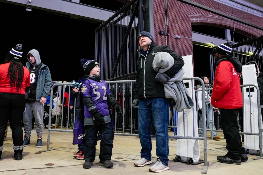 Thomas, 8, and Andy Claxton look up at the large TVs showing scores from around the league ahead of a football game between the Baltimore Ravens and the New England Patriots at M&T Bank Stadium in Baltimore, Md. on Sunday, December 21, 2025. The Sunday Night Football game was the Ravens’ final home game of the regular season.