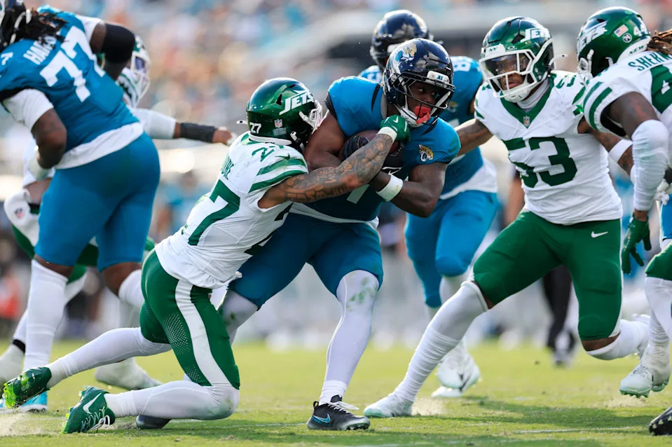 Jacksonville Jaguars running back Travis Etienne Jr. (1) rushes for yards against New York Jets safety Malachi Moore (27) during the third quarter of a NFL football matchup at EverBank Stadium, Sunday, Dec. 14, 2025, in Jacksonville, Fla. The Jaguars defeated the Jets 48-20. [Corey Perrine/Florida Times-Union]
