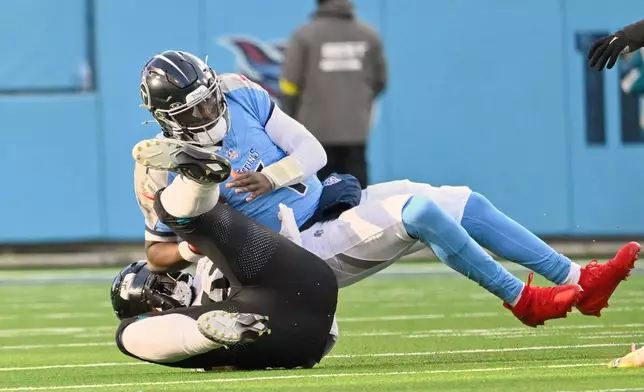 Jacksonville Jaguars defensive end Josh Hines-Allen, left, sacks Tennessee Titans quarterback Cam Ward during the second half of an NFL football game Sunday, Nov. 30, 2025, in Nashville, Tenn. (AP Photo/John Amis)
