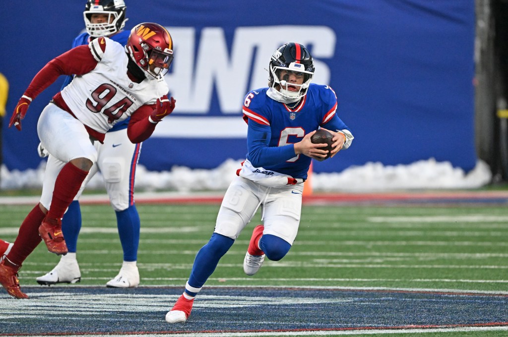 Quarterback Jaxson Dart #6 of the New York Giants runs with the ball while being pursued by a Washington Commanders player.