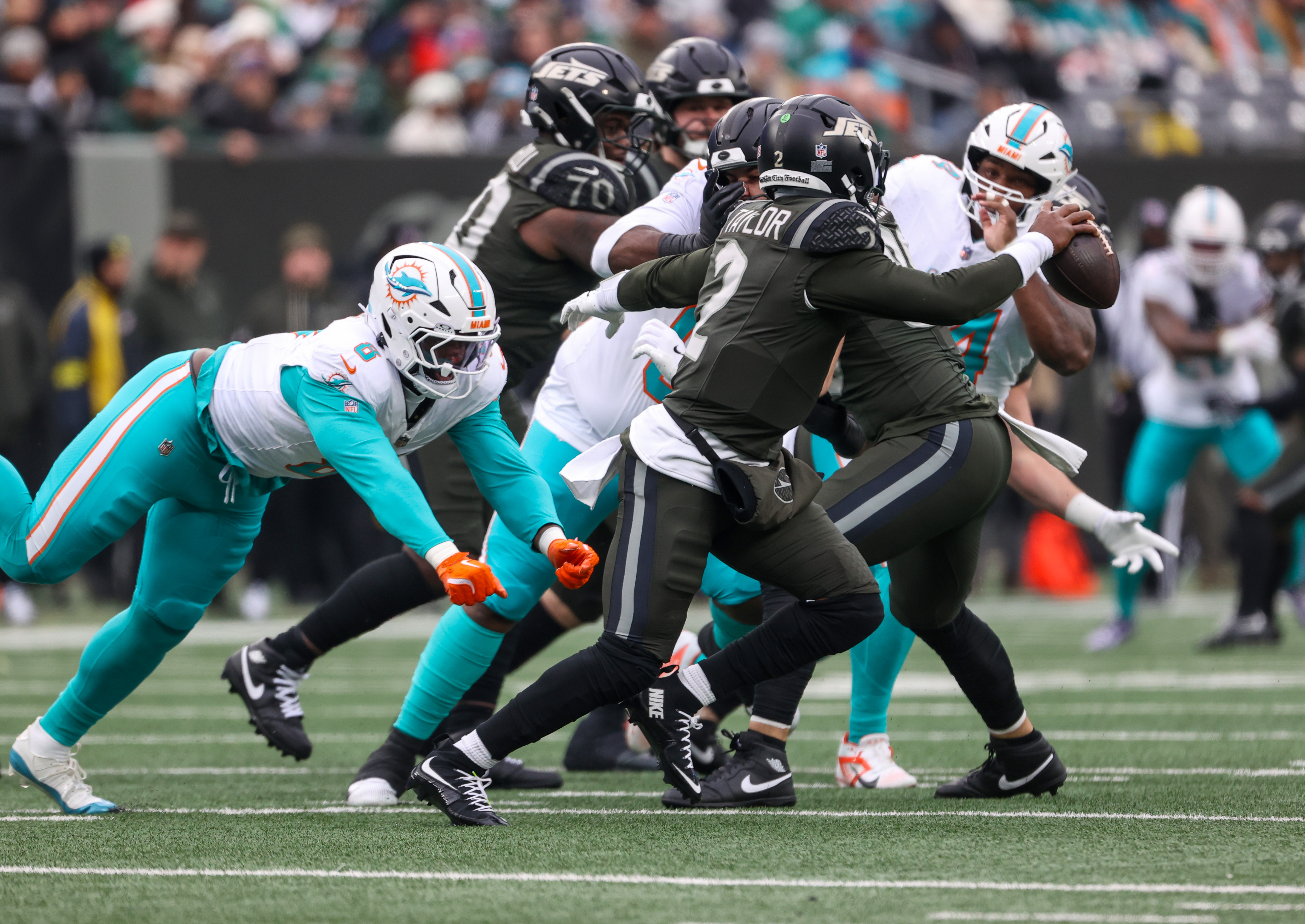 New York Jets quarterback Tyrod Taylor (2) eludes Miami Dolphins linebacker Matthew Judon (8) during the first quarter, Sunday, Dec. 7, 2025 at MetLife Stadium in East Rutherford, N.J. Taylor left the game in the first quarter with a groin injury he may have suffered on this play.