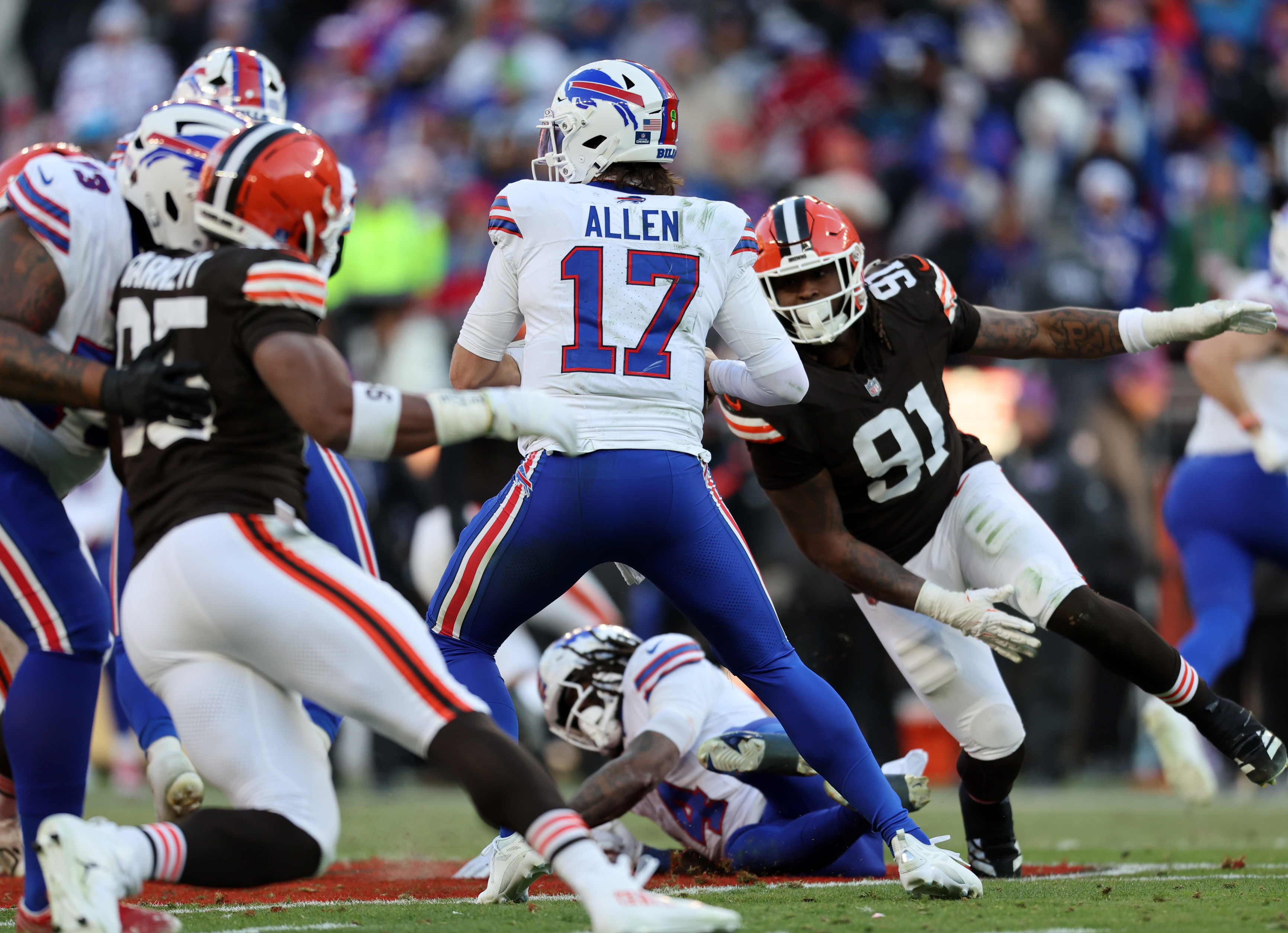 Buffalo Bills quarterback Josh Allen scrambles as he’s pressured by Cleveland Browns defensive end Alex Wright and Cleveland Browns defensive end Myles Garrett in the second half. 