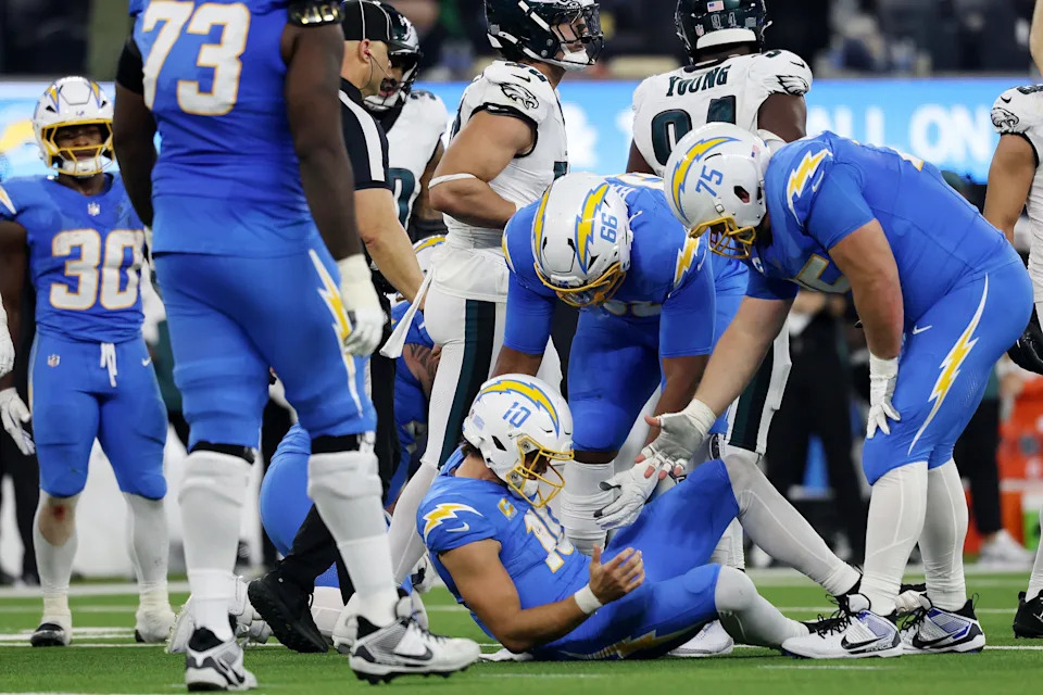 INGLEWOOD, CALIFORNIA - DECEMBER 08: Bobby Hart #66 and Bradley Bozeman #75 help up Justin Herbert #10 of the Los Angeles Chargers after he was sacked by the Philadelphia Eagles during the third quarter at SoFi Stadium on December 08, 2025 in Inglewood, California. (Photo by Katelyn Mulcahy/Getty Images)