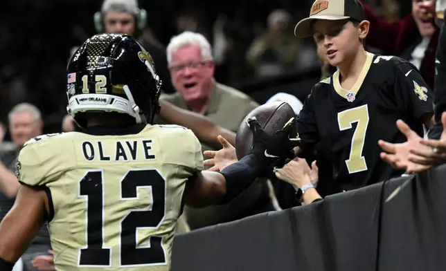 New Orleans Saints wide receiver Chris Olave celebrates hands the ball to a fan after scoring a touchdown during the second half of an NFL football game against the New York Jets, Sunday, Dec. 21, 2025, in New Orleans. (AP Photo/Ella Hall)
