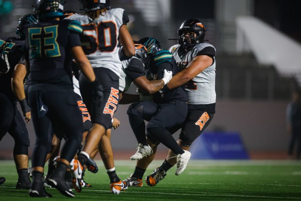 McClymonds' Koi Taiese (51) and McClymonds' Philip Mcelroy (55) tackle Kennedy-Delano's Jamison Membreve (41) in the first quarter during the Division 3-A state championship football game at Fullerton Union High School District Stadium in Fullerton, Calif., on Saturday, Dec. 13, 2025. (Shae Hammond/Bay Area News Group)
