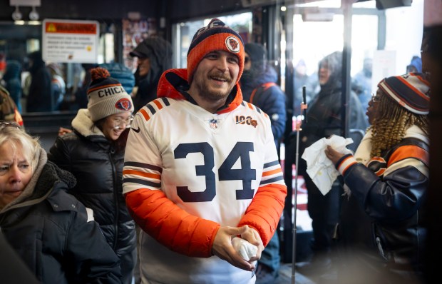 Preston Kennicker picks up a free hot dog as Bears fans line up, Dec. 2, 2025, at The Wieners Circle in Chicago's Lincoln Park neighborhood after coach Ben Johnson took his shirt off in a postgame celebration for a win over the Eagles. (Brian Cassella/Chicago Tribune)