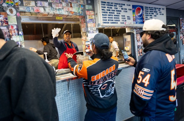Bears fans line up for free hot dogs, Dec. 2, 2025, at The Wieners Circle in Chicago's Lincoln Park neighborhood after coach Ben Johnson took his shirt off in a postgame celebration for a win over the Eagles. (Brian Cassella/Chicago Tribune)