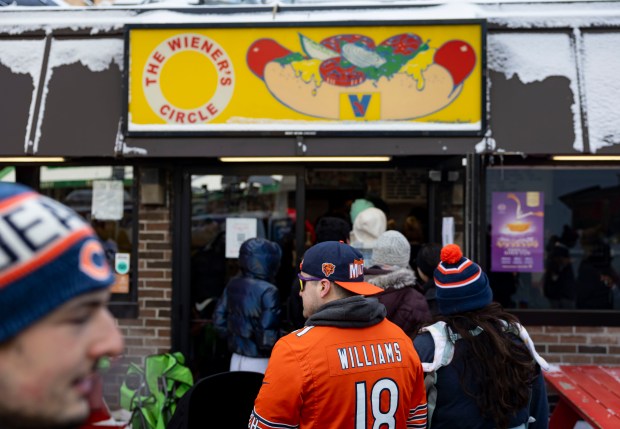 Bears fans line up for free hot dogs, Dec. 2, 2025, at The Wieners Circle in Chicago's Lincoln Park neighborhood after coach Ben Johnson took his shirt off in a postgame celebration for a win over the Eagles. (Brian Cassella/Chicago Tribune)