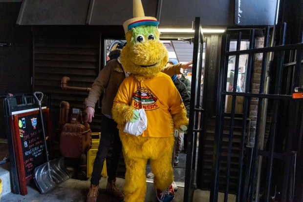 A Chicago Dogs mascot exits as Bears fans line up for free hot dogs, Dec. 2, 2025, at The Wieners Circle in Chicago's Lincoln Park neighborhood after coach Ben Johnson took his shirt off in a postgame celebration for a win over the Eagles. (Brian Cassella/Chicago Tribune)
