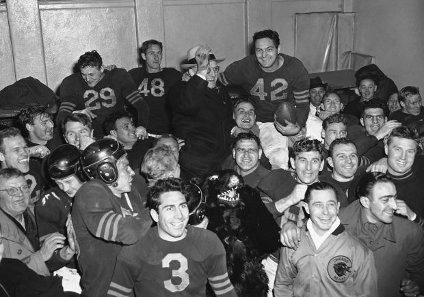 Members of the Chicago Bears football team hoist George Halas (center, waving glove hand), owner and coach, and Sid Luckman (42), Bears quarterback, to their shoulders as they congregate in their locker room at the Polo Grounds in New York, on Dec. 15, 1946, after defeating the New York Giants, 24-14, to win the national football league championship. (J.D. Collins/AP)