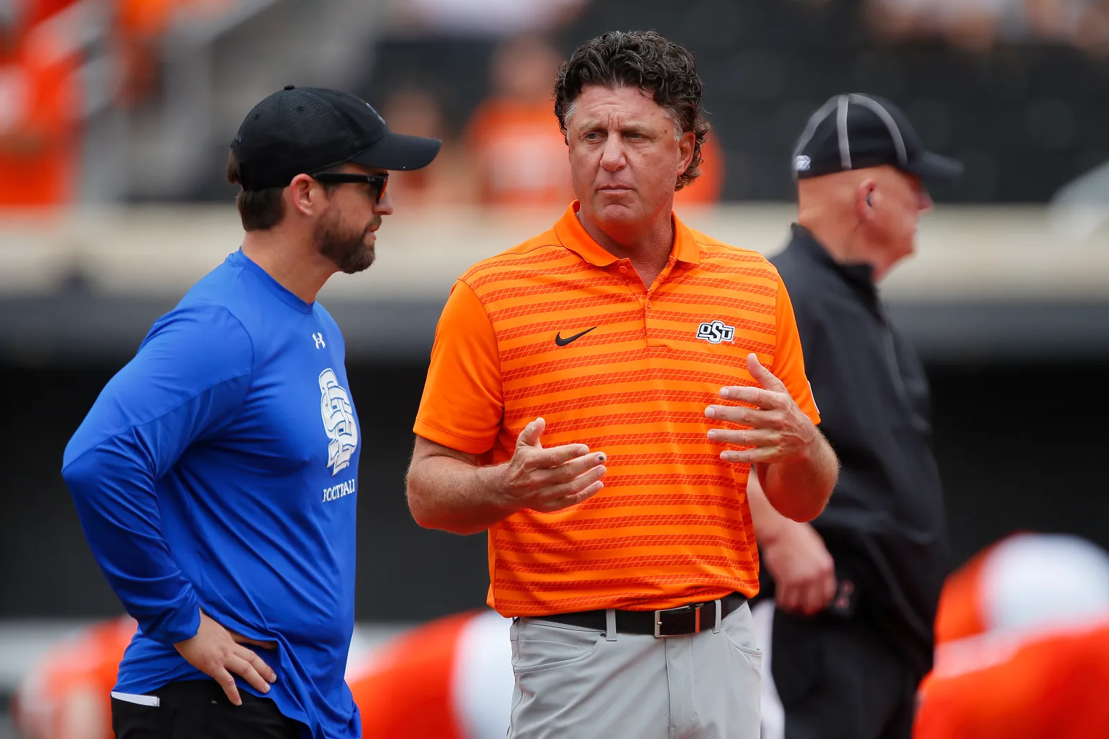 College football head coach Mike Gundy of the Oklahoma State Cowboys talks with head coach Jimmy Rogers of the South Dakota State Jackrabbits