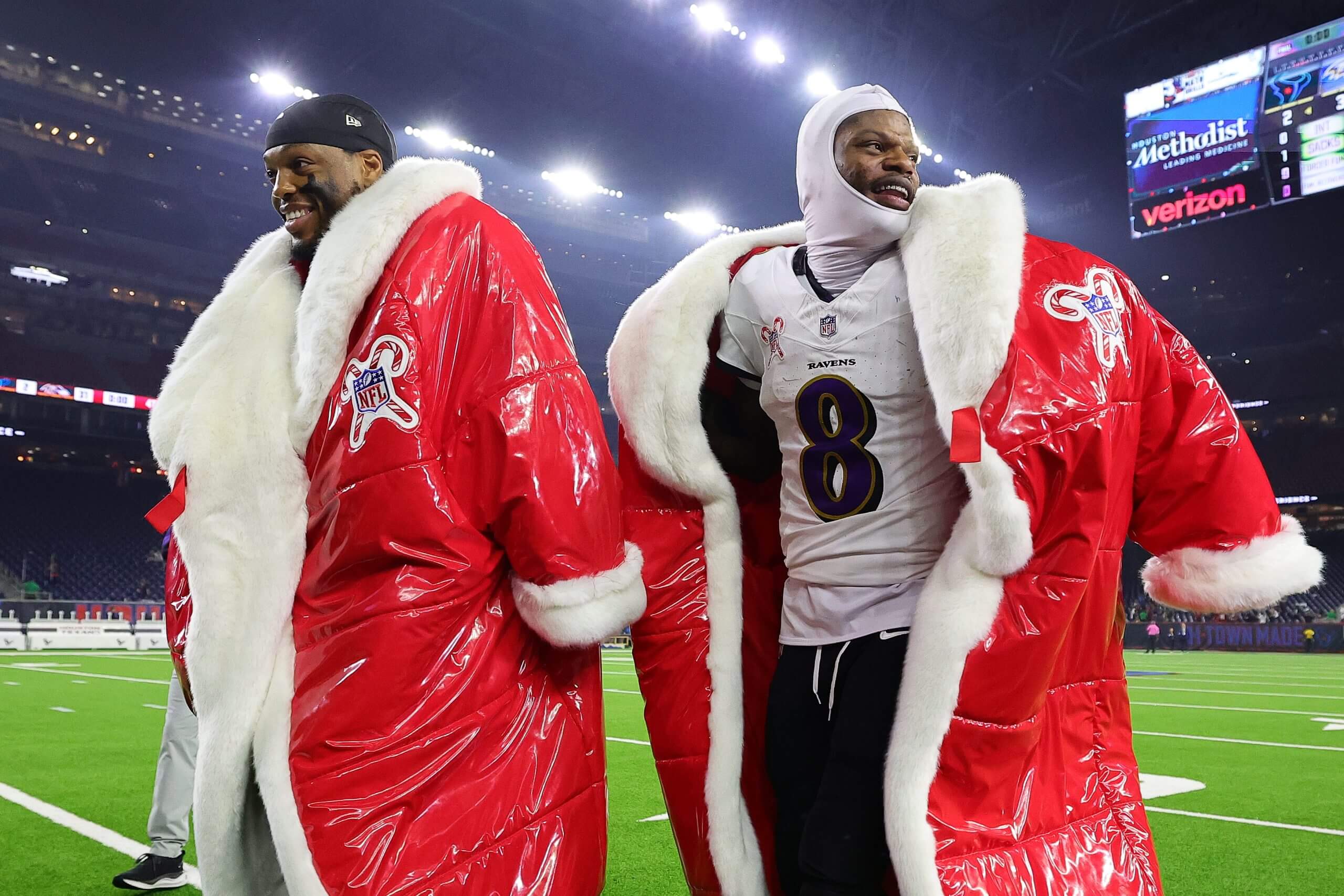 Derrick Henry, left, and Lamar Jackson, right, wear large red Christmas coats.