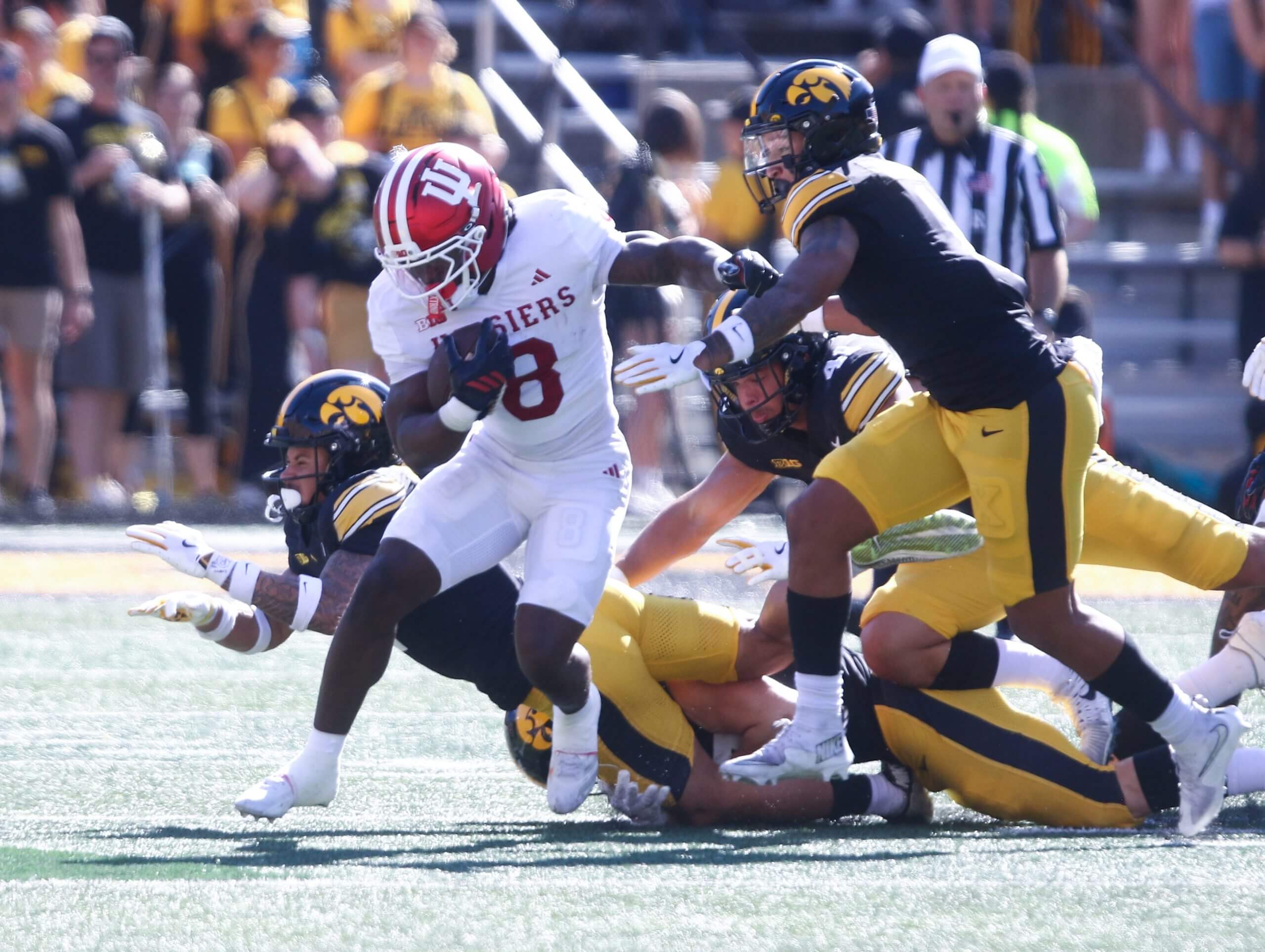 Kaelon Black runs with the football with Iowa defenders trailing him.