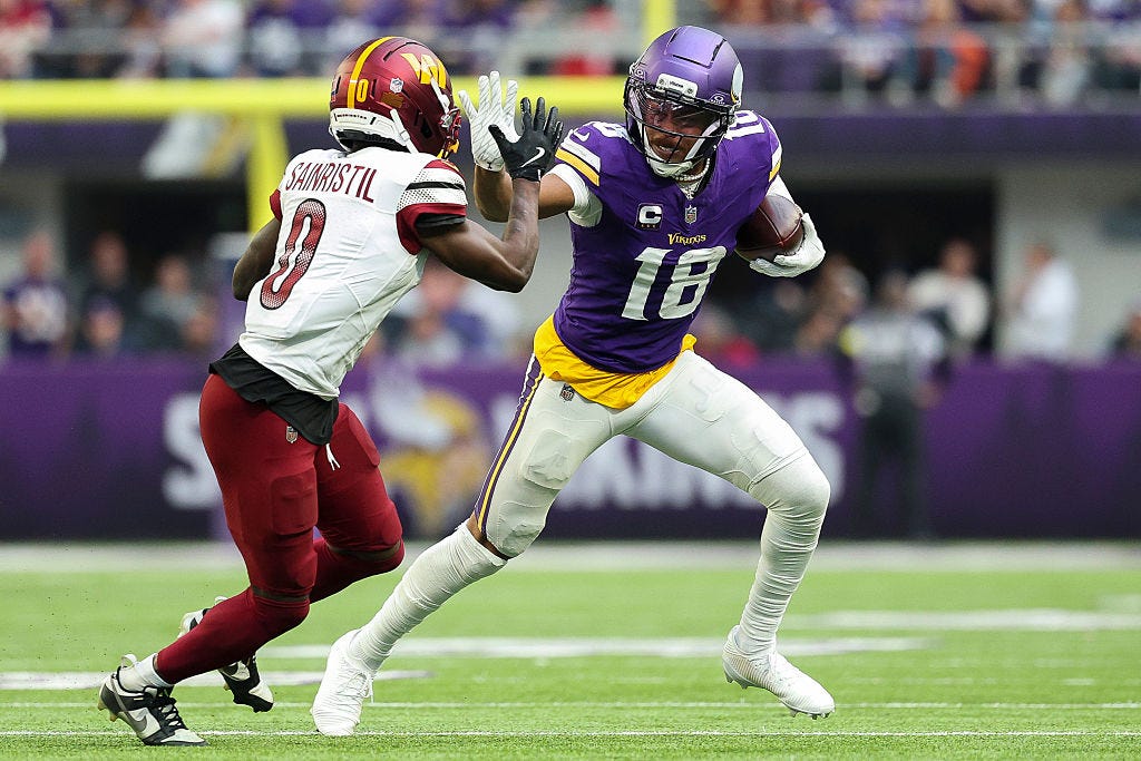 Justin Jefferson #18 of the Minnesota Vikings runs with the ball against Mike Sainristil #0 of the Washington Commanders during the third quarter at U.S. Bank Stadium on December 07, 2025 in Minneapolis, Minnesota.