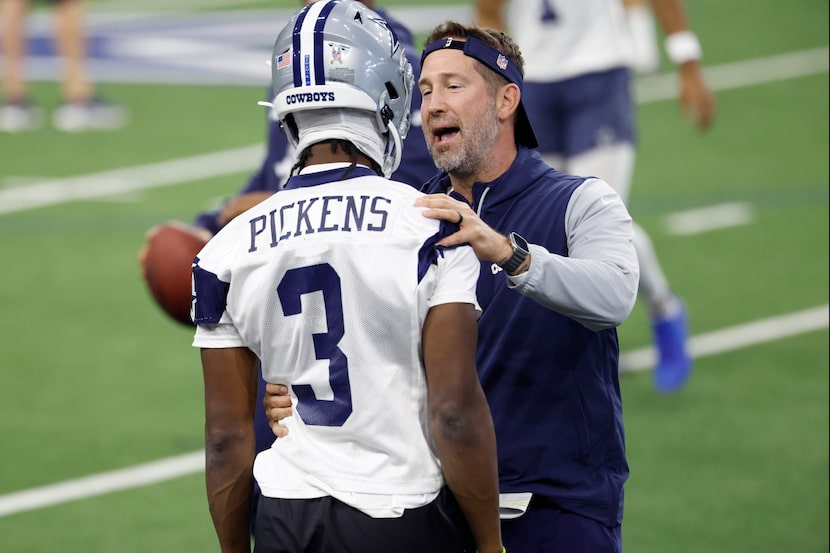 Dallas Cowboys head coach Brian Schottenheimer visits with wide receiver George Pickens (3)...