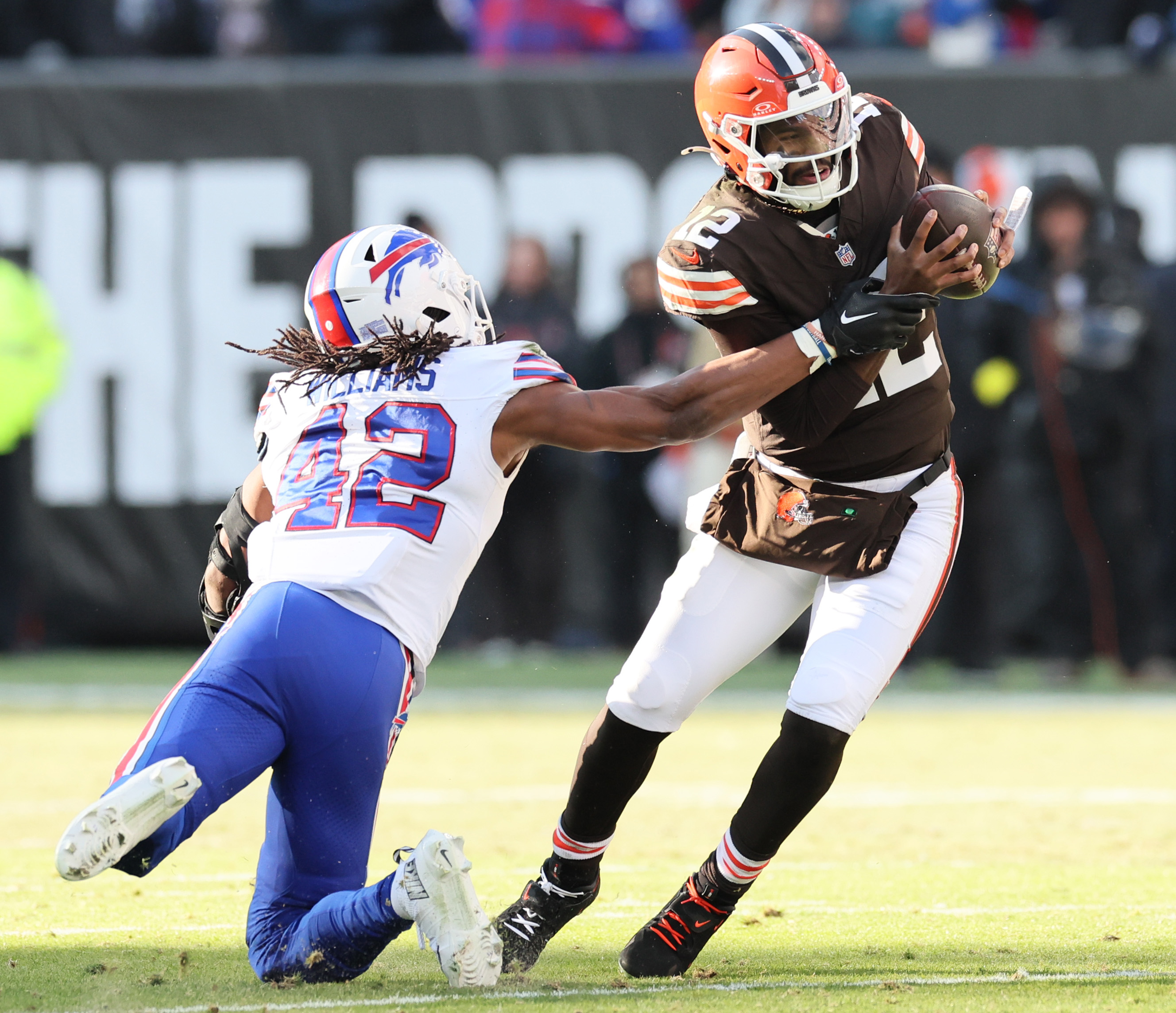 Cleveland Browns quarterback Shedeur Sanders eludes the tackle attempt by Buffalo Bills linebacker Dorian Williams on a pass play in the first half.  
