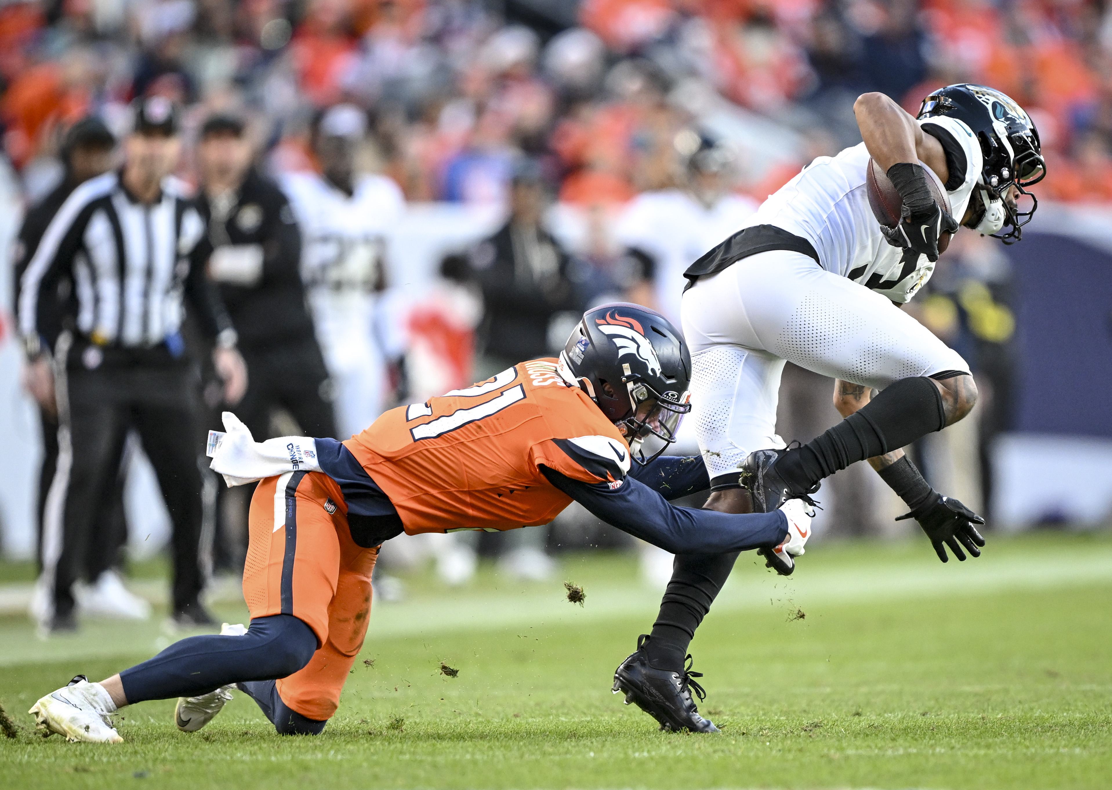 Riley Moss (21) of the Denver Broncos tackles Jakobi Meyers...