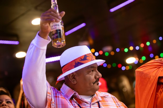 Bronco Gang member since 2014, Hugo "Gizmo" Santillan, 51, raises his beer in the air as Andrew Young, The Mad Fanatic, performs at The Point Sports Bar and Grill in Thornton on Saturday, Nov. 15, 2025. (Photo by McKenzie Lange/Special to The Denver Post)