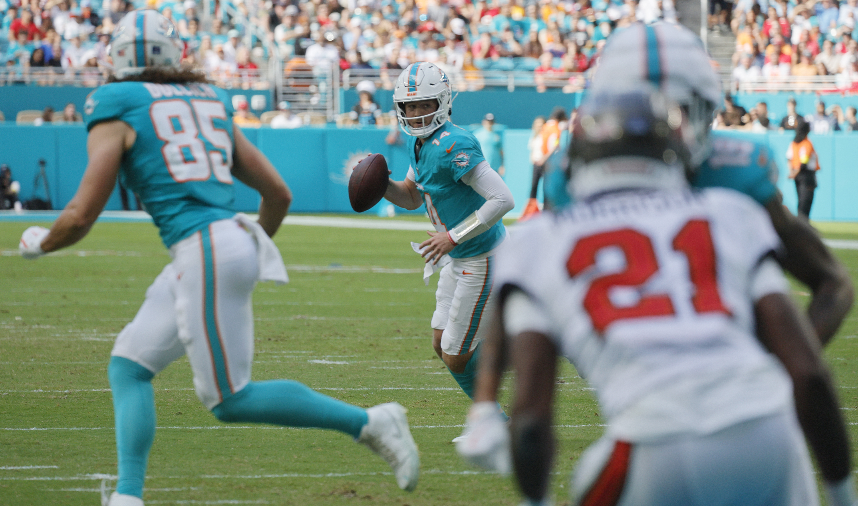 Miami Dolphins quarterback Quinn Ewers (14) rolls out to pass...