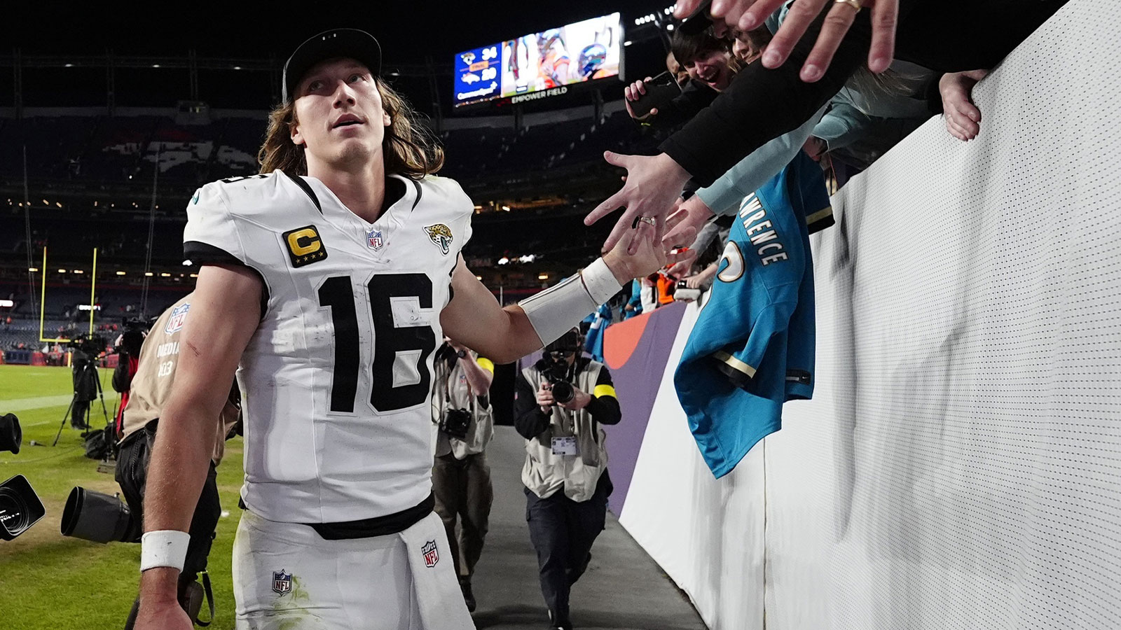Jacksonville Jaguars quarterback Trevor Lawrence (16) shakes hands with fans after the game at Empower Field at Mile High. Mandatory Credit: Ron Chenoy-Imagn Images