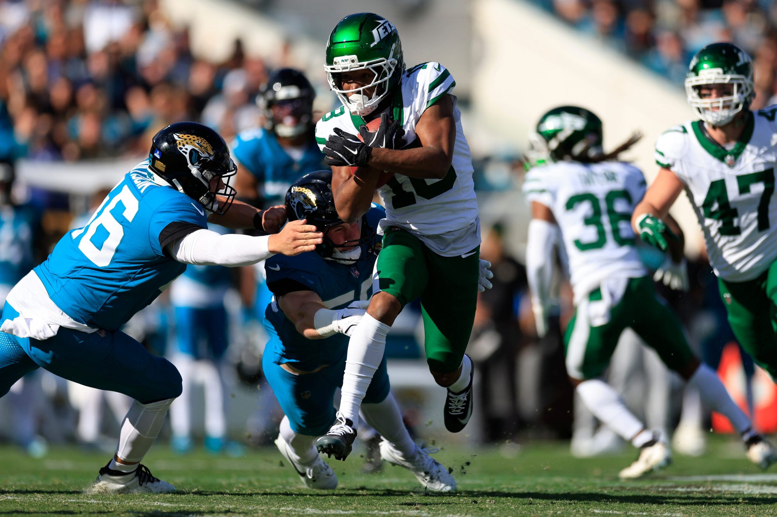 New York Jets wide receiver Isaiah Williams (18) avoids the the tackle from Jacksonville Jaguars linebacker Branson Combs (50), back, and long snapper Ross Matiscik (46), left, during the second quarter of an NFL football matchup at EverBank Stadium, Sunday, Dec. 14, 2025, in Jacksonville, Fla. The Jaguars defeated the Jets 48-20. [Corey Perrine/Florida Times-Union]