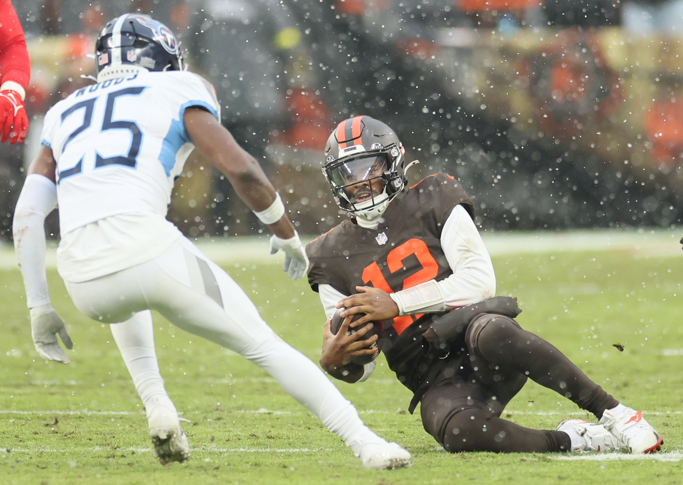 Cleveland Browns quarterback Shedeur Sanders slides to the turf on a keeper before being hit by Tennessee Titans safety Xavier Woods in the first half at Huntington Bank Field.