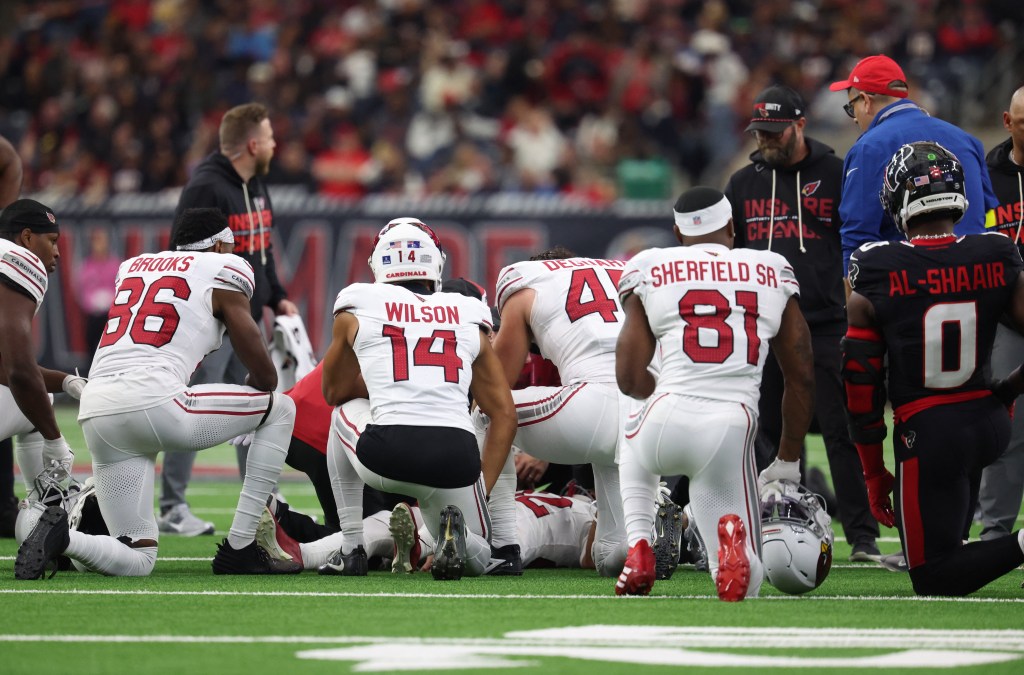 Arizona Cardinals players kneel as wide receiver Andre Baccellia (82) is treated by medical personnel following an injury on a kickoff return.