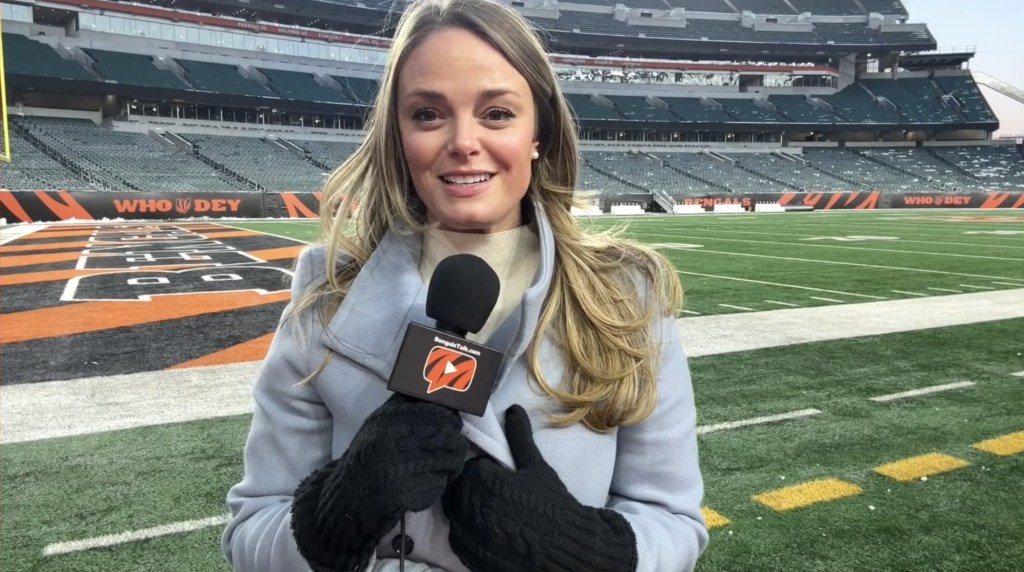 Elise Jesse, a Bengals reporter, holding a microphone in a stadium.
