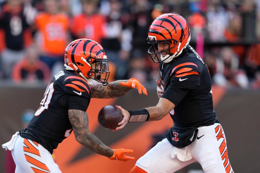 Cincinnati Bengals quarterback Joe Flacco hands the ball off to running back Chase Brown.
