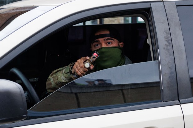 A federal agent points his gun sideways during an immigration enforcement action in the Little Village neighborhood on Nov. 8, 2025. Longtime urban police leaders questioned that tactic and many others used by immigration agents during Operation Midway Blitz. The policing leaders said the agents routinely behaved in ways that beyond potentially being unconstitutional unnecessarily endangered suspects, protesters, innocent bystanders and the agents themselves. (Armando L. Sanchez/Chicago Tribune)