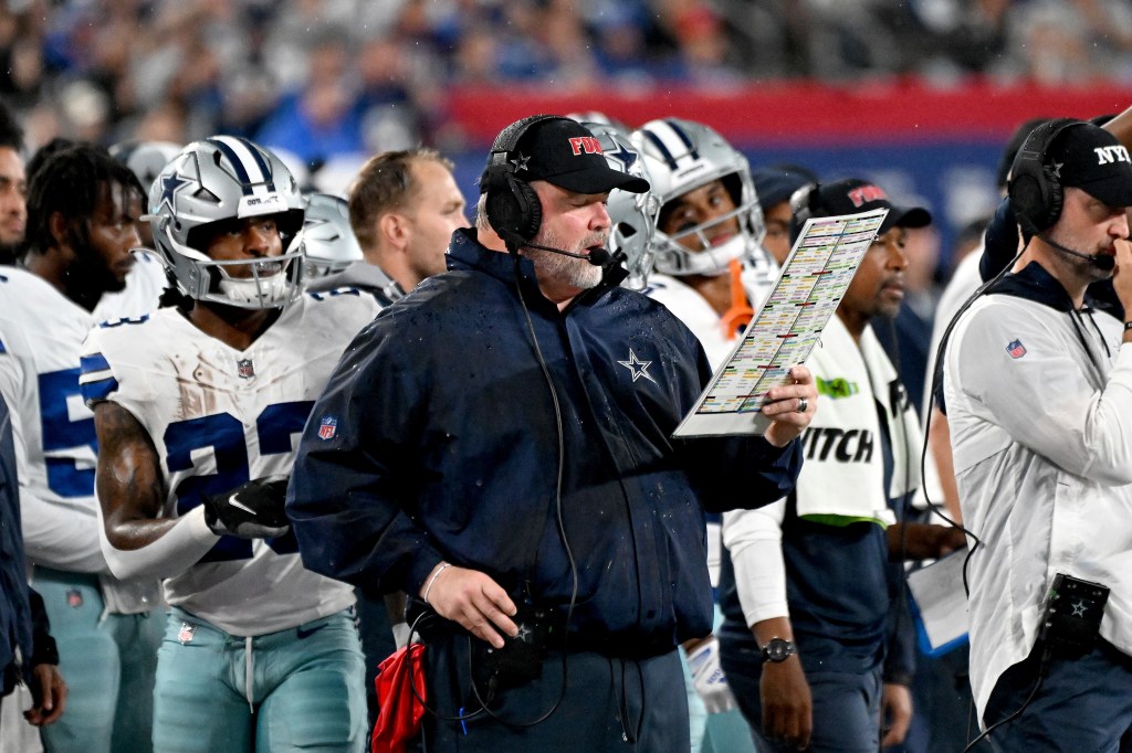 Dallas Cowboys head coach Mike McCarthy on the sideline holding a play chart.