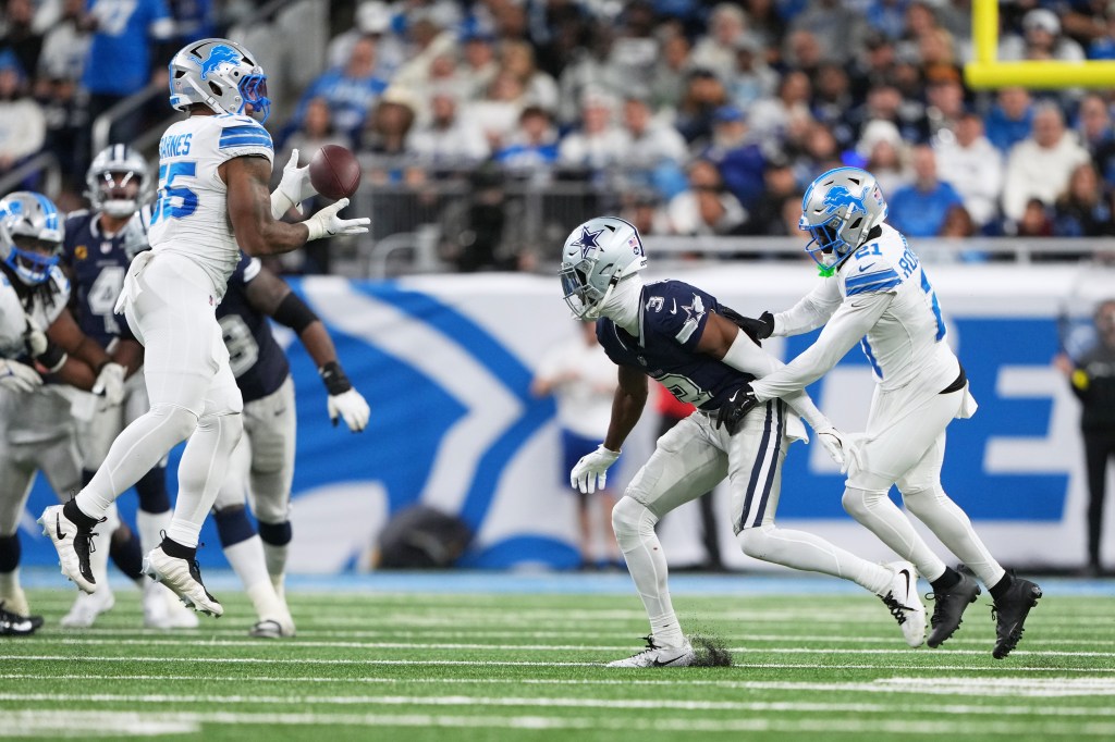 Detroit Lions linebacker Derrick Barnes intercepts a pass intended for Dallas Cowboys wide receiver George Pickens, with Lions teammate Amik Robertson also defending.