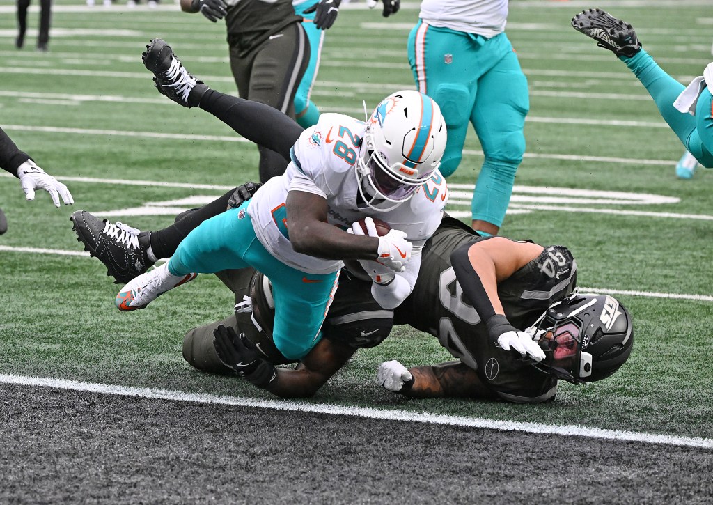 Dolphins running back De'Von Achane (28) runs the ball for a touchdown against a Jets player.