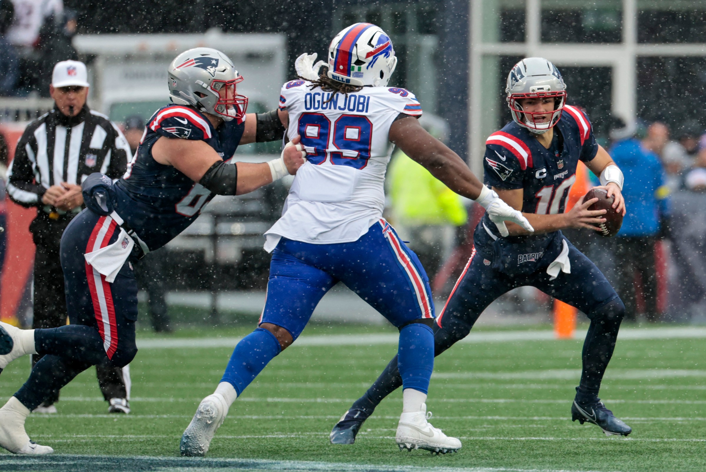 FOXBOROUGH, MA - DECEMBER 14: Drake Maye #10 of the New England Patriots looks to escape from Larry Ogunjobi #99 of the Buffalo Bills during a game between the New England Patriots and the Buffalo Bills on December 14, 2025, at Gillette Stadium in Foxborough, Massachusetts. (Photo by Fred Kfoury III/Icon Sportswire via Getty Images)