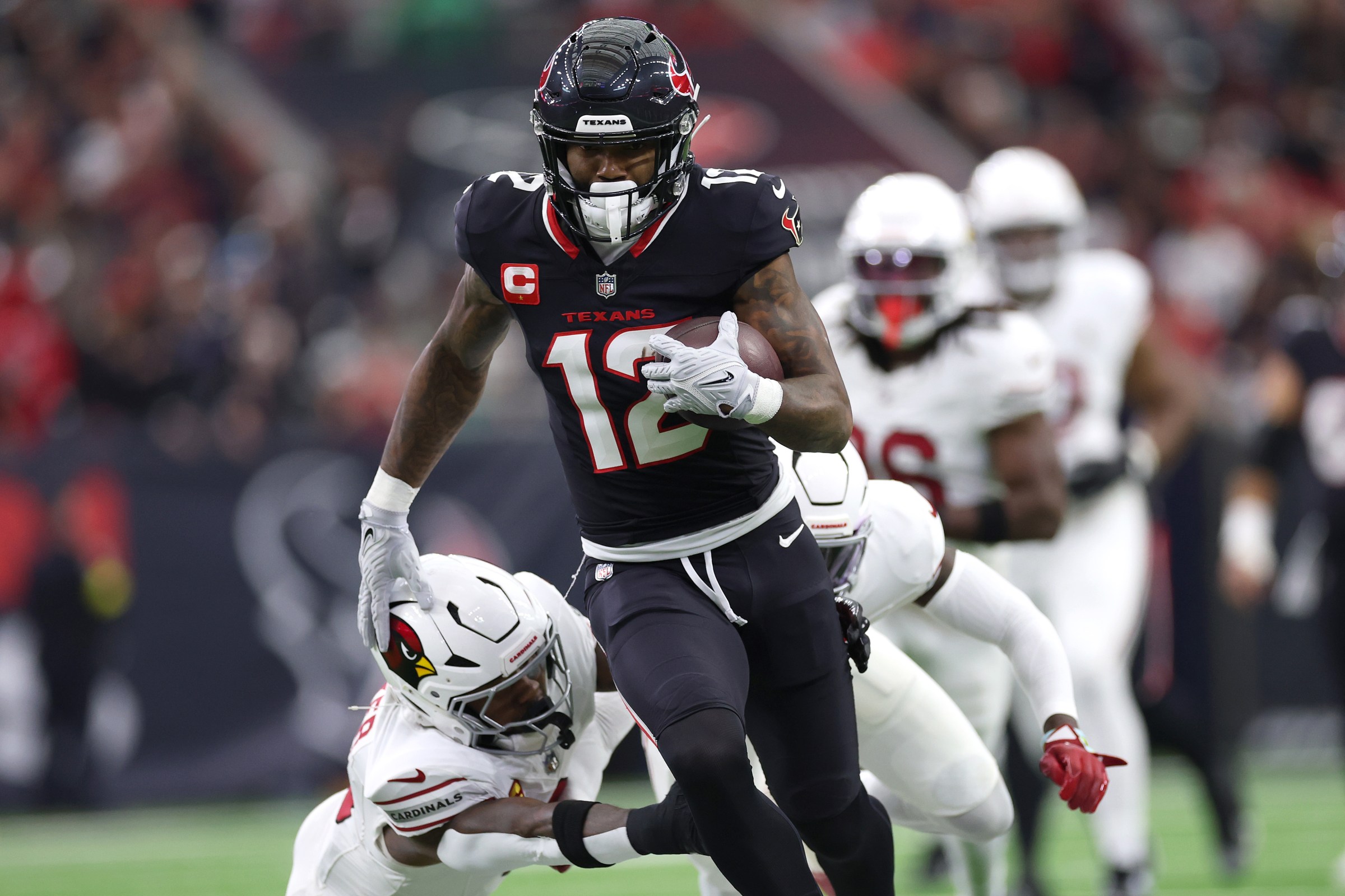 HOUSTON, TEXAS - DECEMBER 14: Nico Collins #12 of the Houston Texans avoids a tackle by Budda Baker #3 of the Arizona Cardinals at NRG Stadium on December 14, 2025 in Houston, Texas. (Photo by Tim Warner/Getty Images)