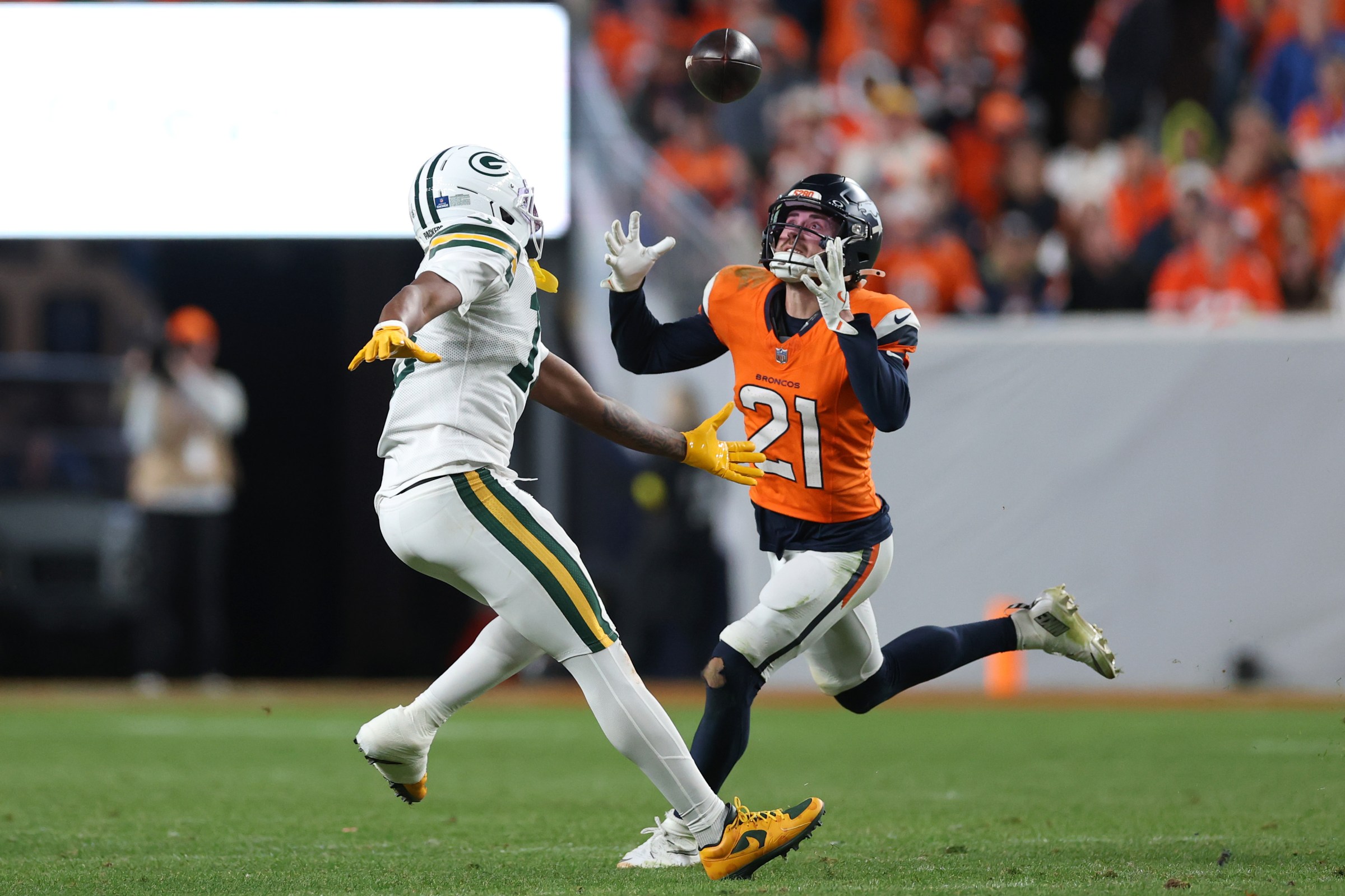 DENVER, COLORADO - DECEMBER 14: Riley Moss #21 of the Denver Broncos catches an interception against Dontayvion Wicks #13 of the Green Bay Packers during the fourth quarter at Empower Field At Mile High on December 14, 2025 in Denver, Colorado. (Photo by Matthew Stockman/Getty Images)