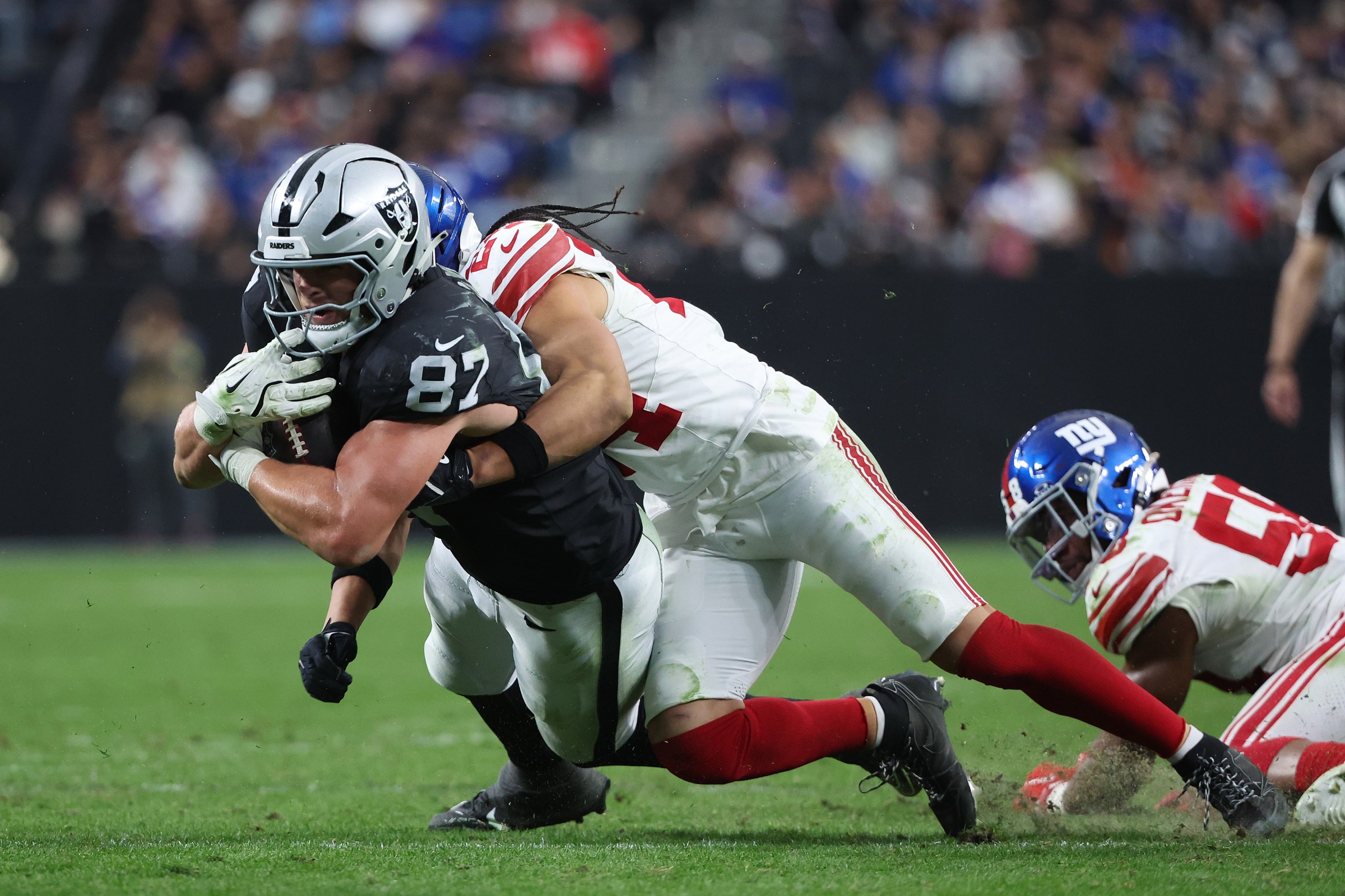 LAS VEGAS, NEVADA - DECEMBER 28: Michael Mayer #87 of the Las Vegas Raiders is tackled by Dane Belton #24 of the New York Giants in the third quarter of the game at Allegiant Stadium on December 28, 2025 in Las Vegas, Nevada. (Photo by Ian Maule/Getty Images)