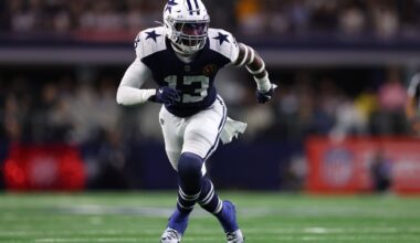 Dallas Cowboys football player running on the field during a game, wearing team uniform and helmet.