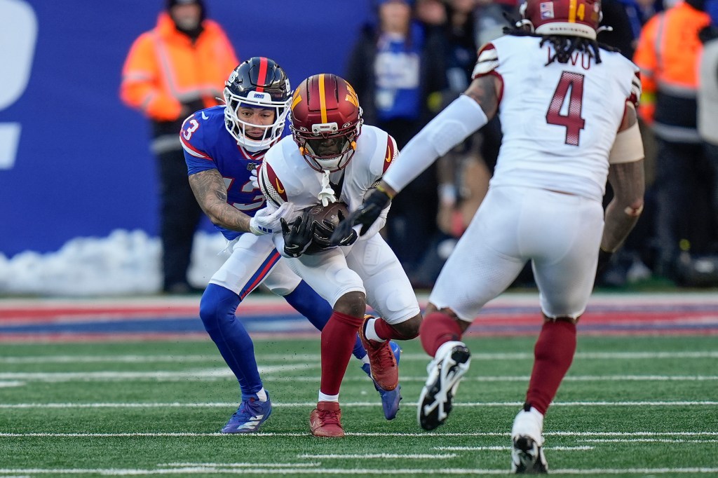 Washington Commanders cornerback Mike Sainristil (0) intercepts a pass intended for New York Giants wide receiver Jalin Hyatt (13) during the second quarter of an NFL football game, Sunday, Dec. 14, 2025, in East Rutherford, N.J.