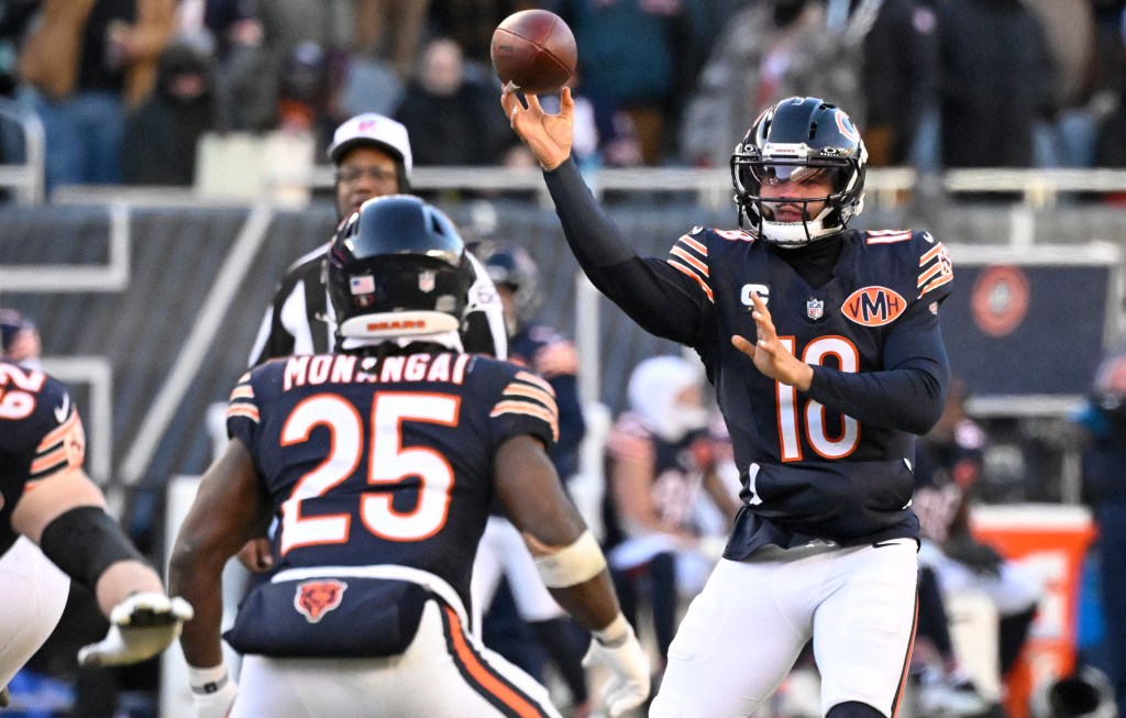 Chicago Bears quarterback Justin Fields throwing the ball with another Bears player in the foreground.