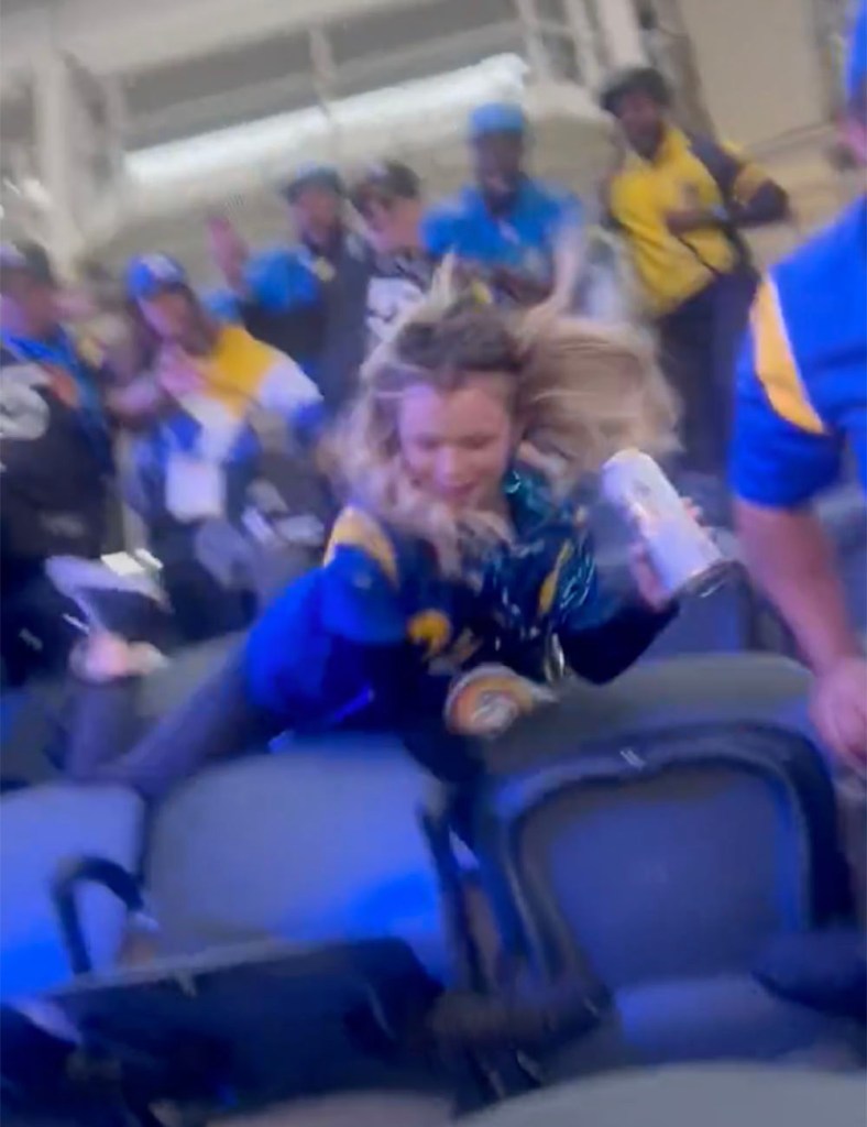 A viral video shows a blonde woman, who's sporting a Rams' Aaron Donald jersey, trying to kick someone before she falls forward and tumbles down a few rows of seats at SoFi Stadium in Inglewood, Calif. on December 14, 2024. 