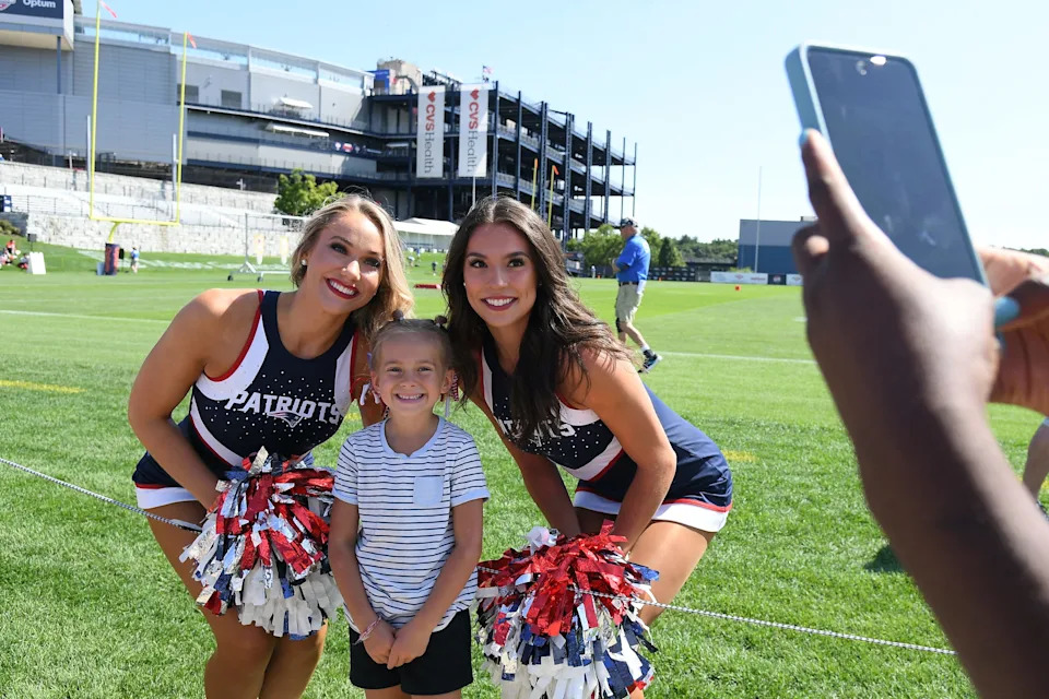 New England Patriots cheerleaders pose with a young fan for a photo during training camp at Gillette Stadium.