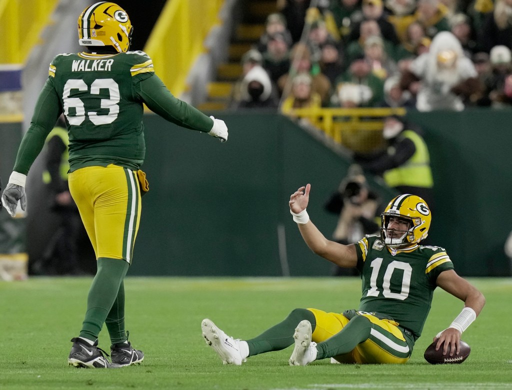 Green Bay Packers quarterback Jordan Love (10) sits on the turf after being sacked, as offensive tackle Rasheed Walker (63) stands nearby.