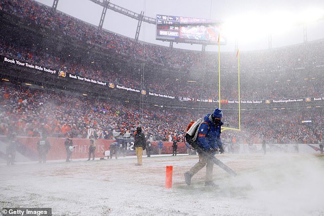 Crew members clear the field of snow during the fourth quarter at Empower Field
